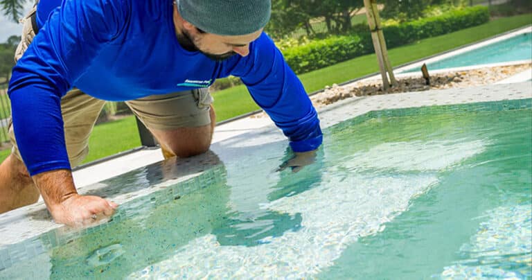 pool repair guy with arm in pool